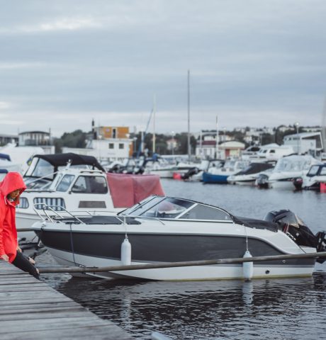 Beautiful young woman in a red cloak in the yacht port. Stockholm, Sweden
